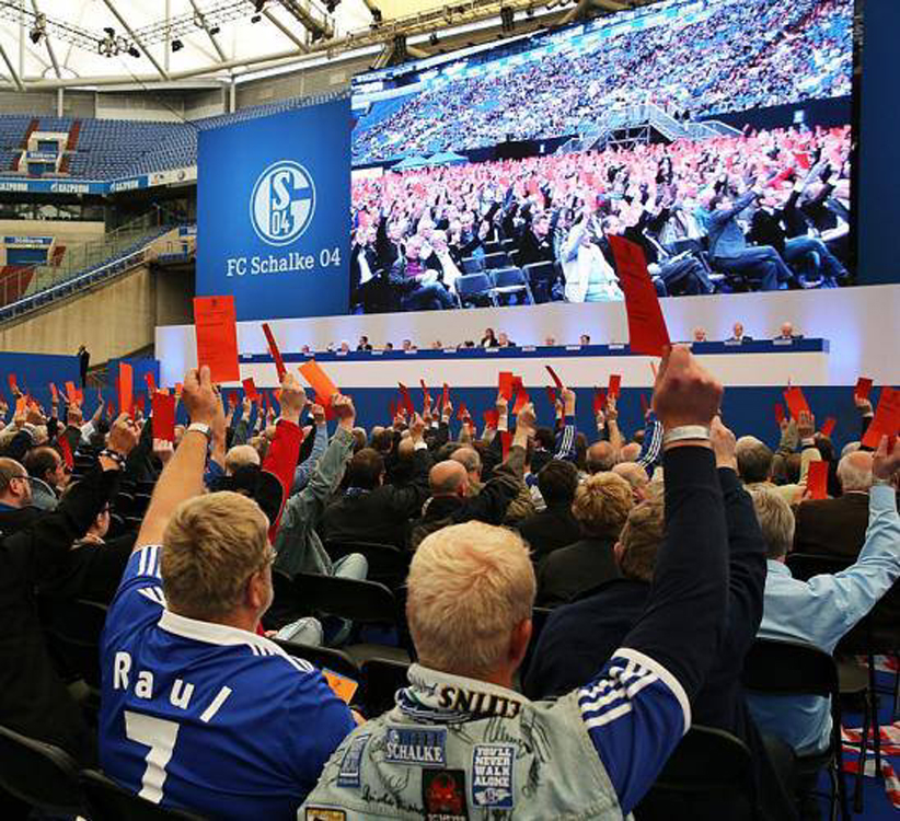 Fans mit roten Abstimmungskarten auf der Schalker Mitgliederversammlung