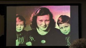 Während des Vortrags wird ein Bild der jungen Familie auf eine Leinwand projiziert.